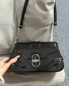 Black patent leather shoulder baguette bag detail, elegant design with metal hardware.