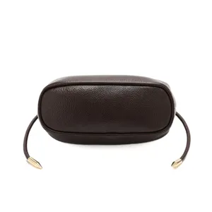 Dark brown leather shoulder bag detail, minimalist dumpling bag bottom view with metallic tips.