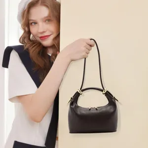 Minimalist black leather shoulder bag with chic gold hardware, versatile commuting tote style.