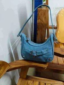 Nahaufnahme der stilvollen hellblauen Jeans-Umhängetasche mit Stern-Metallschließe.