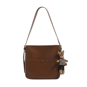 Stylish brown PU leather shoulder bag for women, casual underarm bucket bag with cute bunny charm.