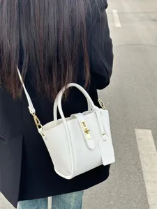 Detailed view of white pebble leather bucket shoulder bag with gold lock hardware charm.