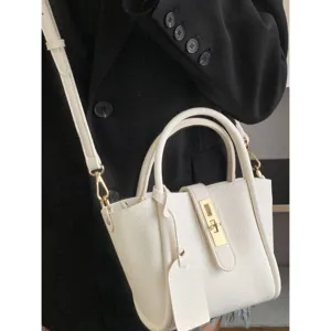 White leather bucket bag detail showing soft lychee grain texture and gold lock hardware.