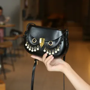 Detailansicht der kreativen Eulen-Satteltasche mit Perlenfransen, schwarzem Leder und goldem Schloss.