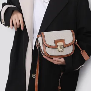 Detail shot of the contrast color saddle bag, featuring canvas and leather trim with metal lock.