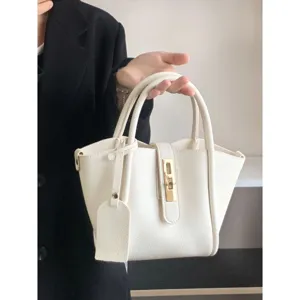 Close-up detail of white pebbled leather handbag featuring gold-tone lock and twin top handles.