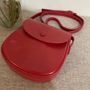 Rote Umhängetasche aus Leder für Damen, schicke Handtasche mit Klappverschluss und schmalem Gurt.
