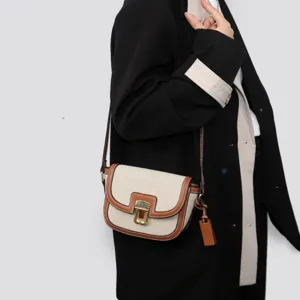 Detailed view of the stylish contrast color saddle bag, showcasing premium canvas and leather trim.