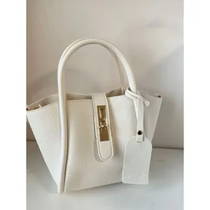Close-up detail of white pebbled soft leather handbag featuring elegant gold metal lock clasp.