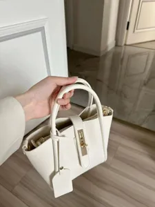 White pebble leather tote bag with metal lock closure and top handles for women daily commute.