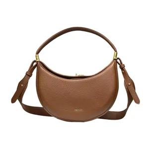 Close-up detail of the brown leather crescent shoulder bag, showing fine texture and hardware.