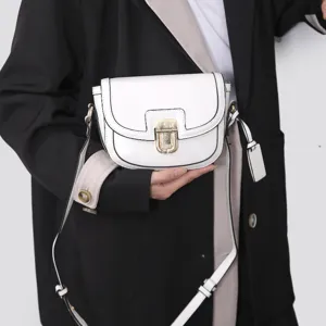 Close-up detail of the stylish white saddle bag with contrast black piping and metal clasp.