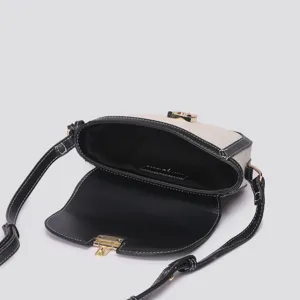 Detail view of the canvas and leather color-blocked saddle bag interior and gold hardware.