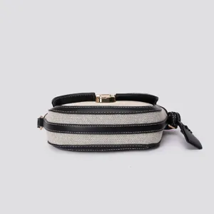 Canvas leather color-block saddle bag detail view showing metal lock and stitching lines.