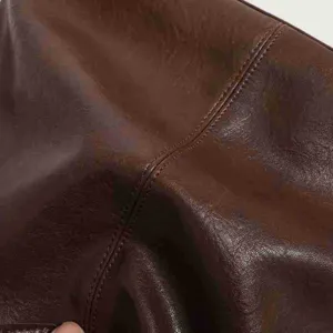 Close-up detail of vintage brown leather texture and neat stitching on women handbag.