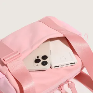 Pink nylon gym duffel bag detail showcasing spacious interior storage capacity and strap.