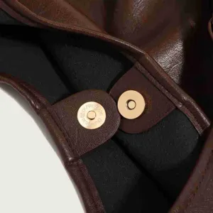 Detailed view of brown leather tote bag magnetic snap closure clasp interior accessory.