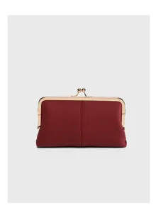 Detailed close-up view of red pebbled leather kiss-lock coin purse with golden frame.