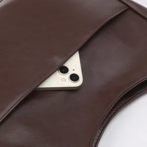 Nahaufnahme Detail der braunen weichen Ledertasche mit praktischer Tasche und Smartphone.