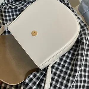 Nahaufnahme der minimalistischen beigen Umhängetasche mit goldenem Magnetverschluss.