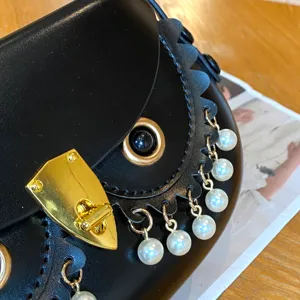Detailaufnahme der Eulentasche mit schwarzem Leder, goldenen Beschlägen und Perlen.