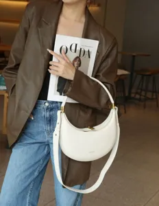 White crescent shoulder bag, stylish leather hobo bag with metal hardware for women daily use.