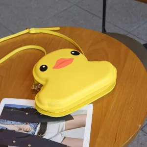 Yellow duck shaped hard shell crossbody bag detail, cute cartoon shoulder bag close up view.