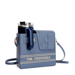 Blue leather water bottle crossbody bag with crocodile flap and embroidered text.