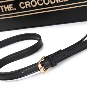 Close-up detail of black leather bag shoulder strap featuring shiny gold metal buckle.
