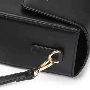 Close-up of black leather bag side, showing metal clasp and shoulder strap detail.
