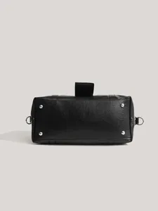 Black leather handbag bottom detail with metal feet and strap design for daily commute.