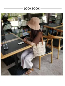 Dettaglio dell'elegante borsa a secchiello in pizzo al bar, grande capienza e stile casual chic.
