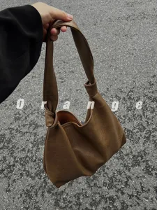 Detailed view of the brown PU leather shoulder bag, highlighting the soft slouchy knotted strap.