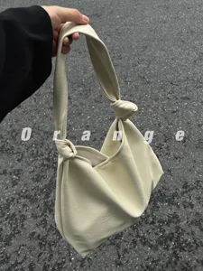 Detail view of the stylish faux leather knotted shoulder bag, soft texture and casual design.