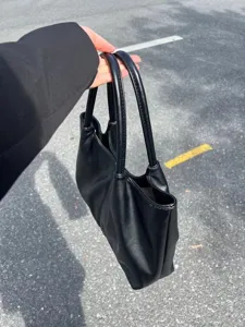 Detailed view of minimalist black leather tote bag handle and soft texture, versatile style.