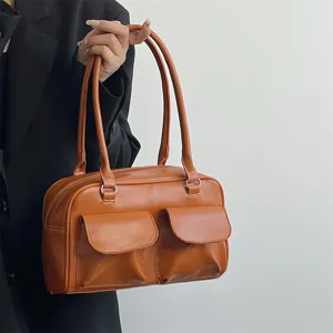 Close-up view of vintage brown leather shoulder bag highlighting dual front pockets and handles.