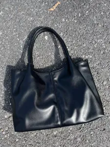 Detailed view of the black minimalist leather tote bag showing texture and vertical sewing.