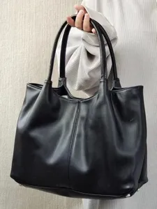 Detailed view of black faux leather tote bag with sturdy double handles and spacious interior.