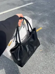 Detailed view of the black leather tote bag showing smooth texture and large capacity handles.
