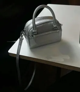 Silver metallic mini top-handle crossbody bag detail shot, compact design with strap.