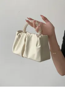 Close-up of elegant pleated cloud handbag with pearl handle, cream white PU leather texture.