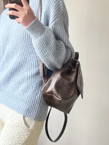 Dettaglio di un mini zaino vintage marrone con coulisse e spallini sottili indossato da una modella.