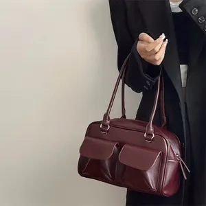 Detailed view of dark red leather shoulder bag with dual front pockets and tote design.