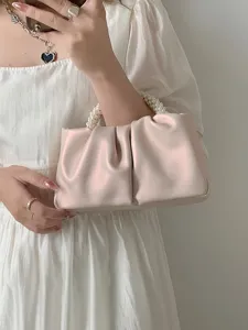 Detailed view of pink ruched cloud bag with elegant pearl handle, showcasing soft texture.