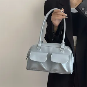 Detailed view of the light blue shoulder bag showcasing dual front pockets and fine texture.