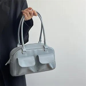 Detail shot of light blue shoulder bag with front pockets and dual handles for daily commute.
