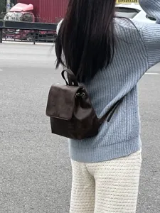 Vista dettagliata del mini zaino marrone vintage indossato all'aperto, stile compatto.