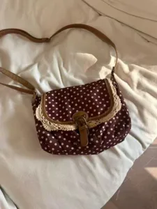 Vintage brown polka dot crossbody bag detail featuring cute lace trim and classic buckle.