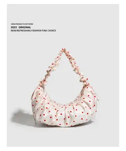 Detail shot of the stylish ruched polka dot dumpling handbag with gathered strap and soft texture.