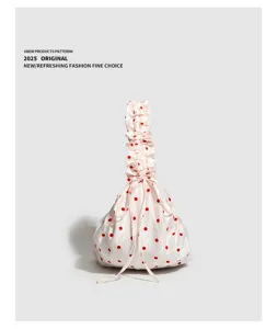 Detailed view of a trendy pleated polka dot drawstring handbag with cute red dots and chic style.
